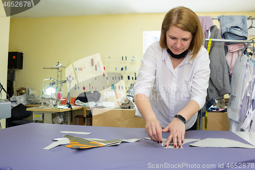 Image of Girl fashion designer puts chalk details on patterns