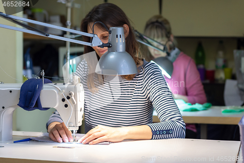 Image of a seamstress scribbles on a sewing machine in a atelier at her workplace