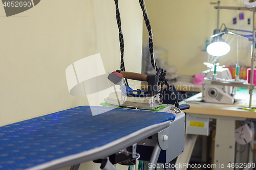 Image of ironing machine with iron in sewing workshop