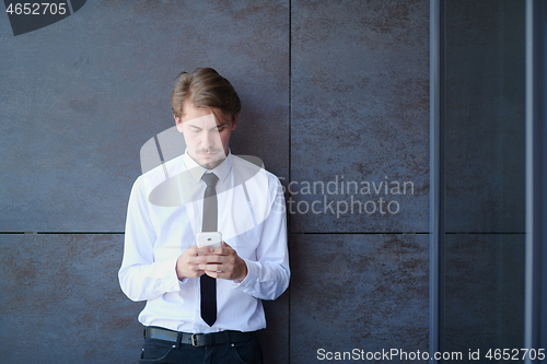 Image of startup businessman in a white shirt with a tie using mobile pho