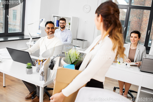 Image of happy businesswoman with personal stuff at office