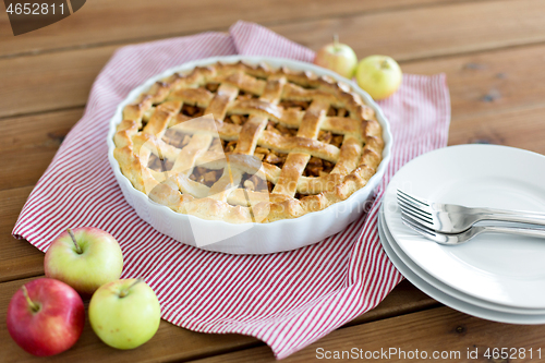 Image of apple pie in baking mold on wooden table