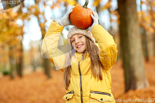 Image of happy girl with pumpkin at autumn park