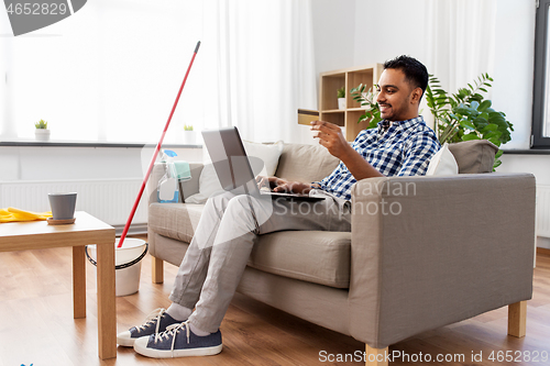 Image of man with laptop shopping online after cleaning