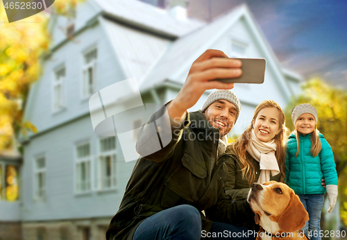 Image of family with dog taking selfie over house in autumn