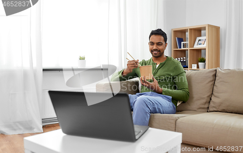 Image of indian man with laptop eating takeout food at home