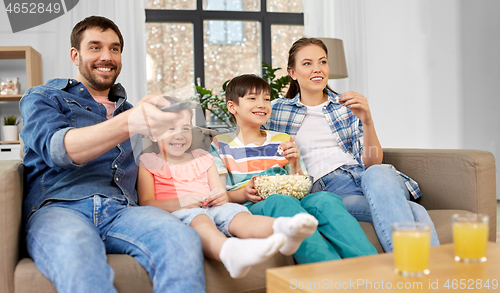 Image of happy family with popcorn watching tv at home