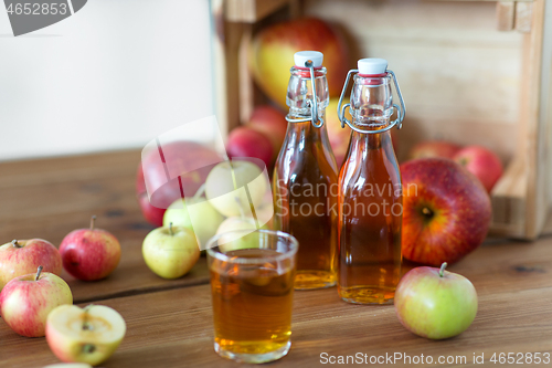 Image of glass and bottles of apple juice on wooden table