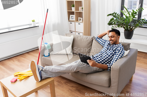 Image of man with tablet computer after home cleaning