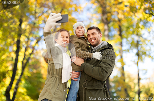 Image of family taking selfie by smartphone in autumn park