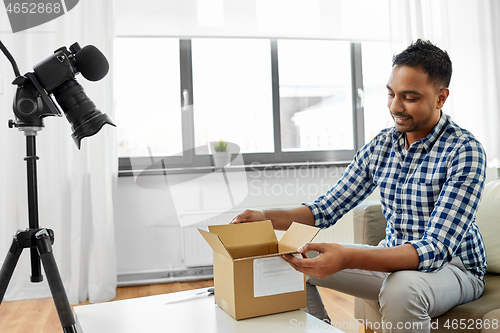 Image of male video blogger opening parcel box at home