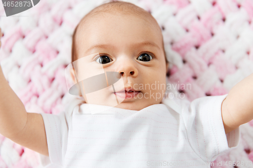 Image of sweet baby girl lying on knitted plush blanket