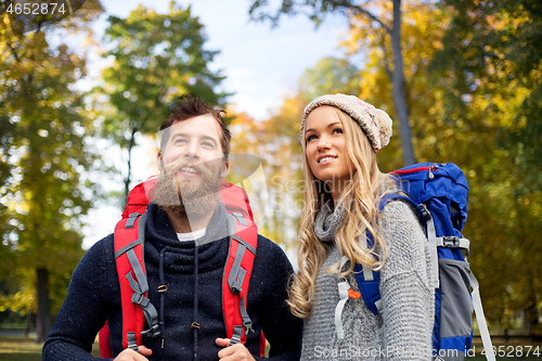 Image of smiling couple with backpacks hiking in autumn