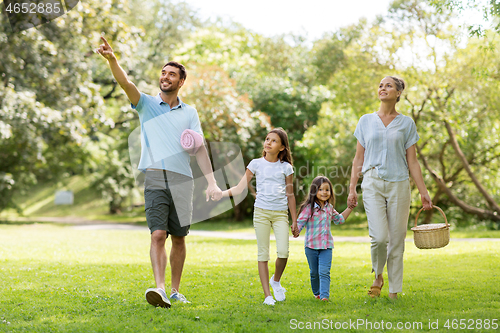 Image of family with picnic basket walking in summer park