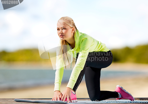 Image of woman stretching on exercise mat on beach