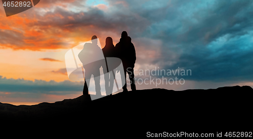 Image of group of travellers with backpacks over sunset