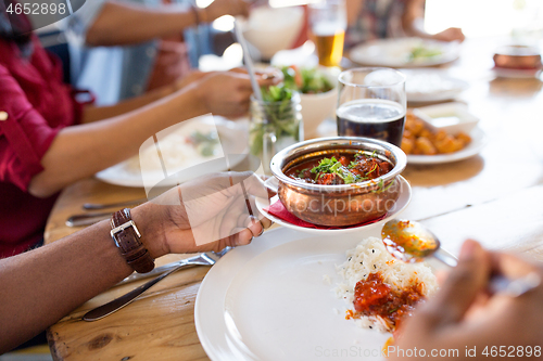 Image of african man eating with friends at restaurant