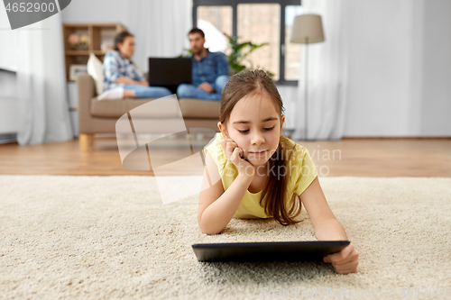 Image of girl with tablet computer lying on floor at home