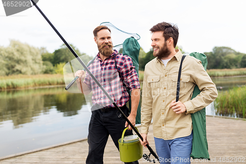 Image of male friends with net and fishing rods on lake