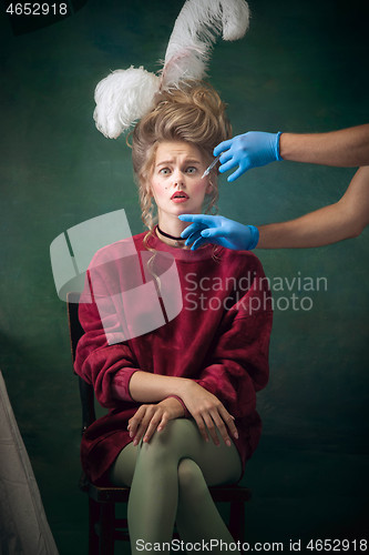 Image of Young woman as Marie Antoinette on dark background. Retro style, comparison of eras concept.