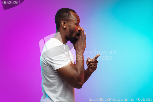 Image of African-american young man\'s portrait on gradient studio background in neon