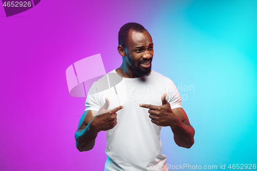 Image of African-american young man\'s portrait on gradient studio background in neon