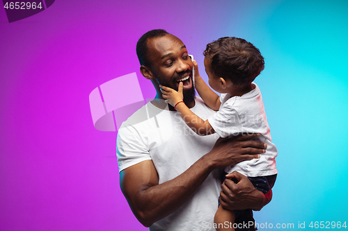 Image of African-american father and son portrait on gradient studio background in neon