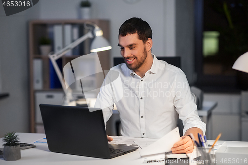 Image of businessman with laptop working at night office