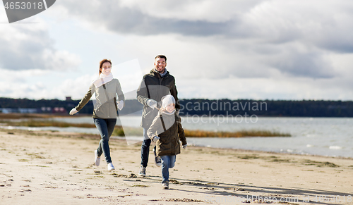 Image of happy family running along autumn beach