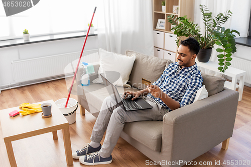 Image of man with laptop shopping online after cleaning