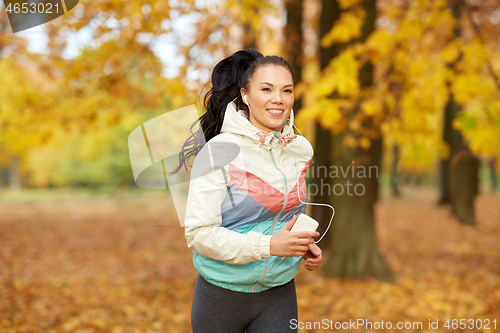 Image of woman running in park and listening to music