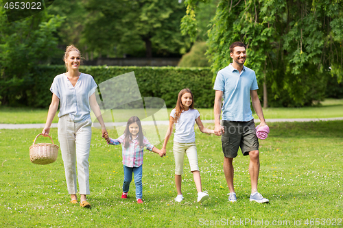 Image of family with picnic basket walking in summer park