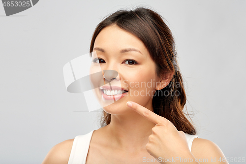 Image of happy smiling young asian woman touching her face