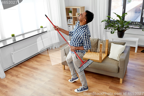 Image of man with broom cleaning and having fun at home