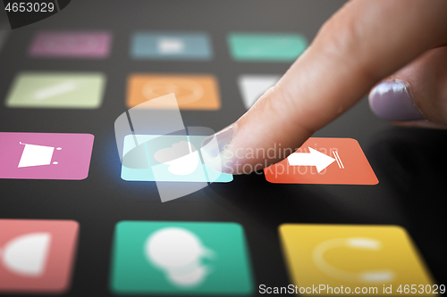 Image of finger touching interactive panel with app icons