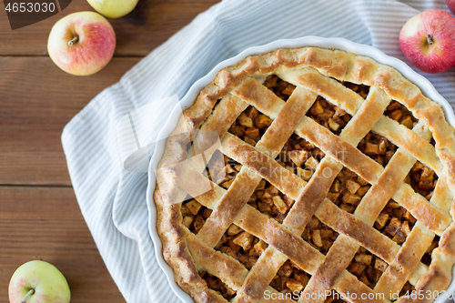 Image of apple pie in baking mold on wooden table