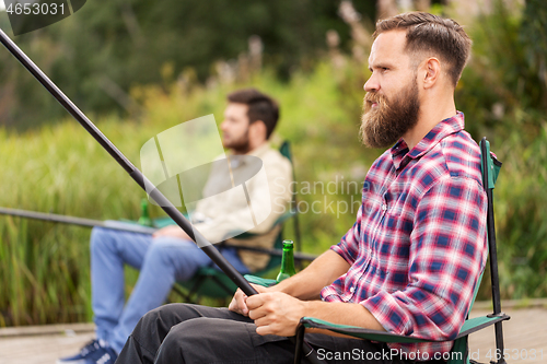 Image of male friends with fishing rods on lake