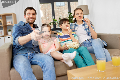 Image of happy family with popcorn watching tv at home