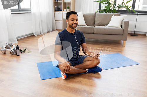 Image of indian man meditating in lotus pose at home