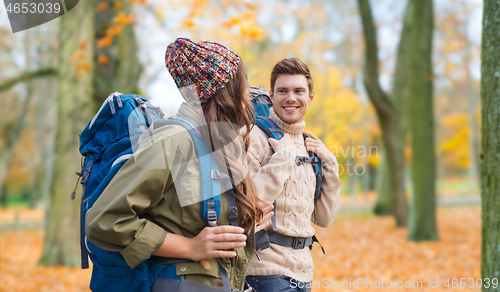 Image of smiling couple with backpacks hiking in autumn