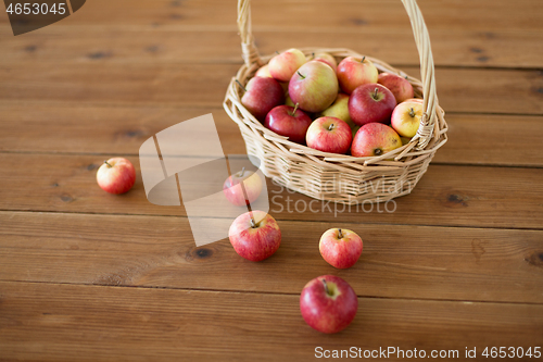 Image of ripe apples in wicker basket on wooden table