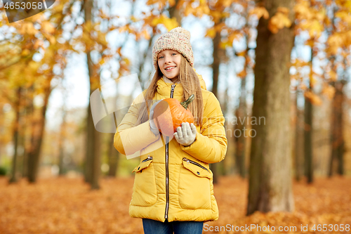 Image of happy girl with pumpkin at autumn park