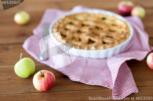 Image of close up of apple pie in baking mold and knife