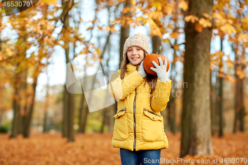 Image of happy girl with pumpkin at autumn park