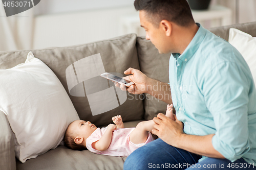 Image of father with smartphone taking picture baby at home