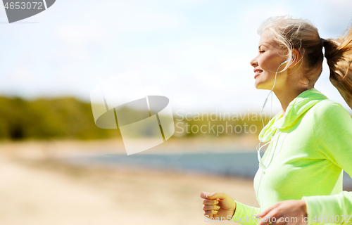 Image of woman with earphones running at park