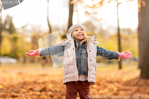 Image of happy little girl with open arms at autumn park