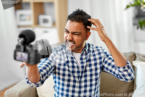 Image of male video blogger with camera blogging at home