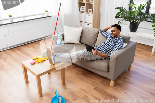 Image of man with tablet computer after home cleaning