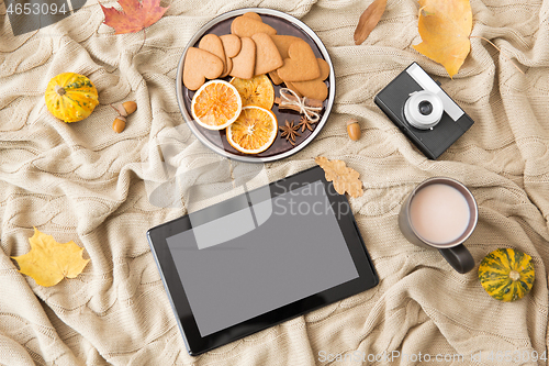 Image of tablet computer, hot chocolate and autumn leaves